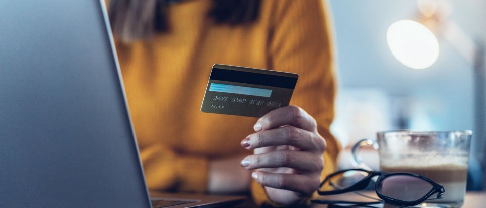 Kvinde foran computer med kreditkort i hånden