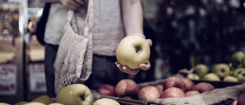 Kvindehånd der holder et æble i supermarkedet