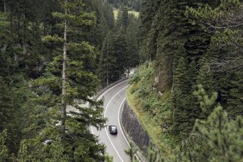 Elbil eller plug in hybrid - bil kører på kurvet vej i skov