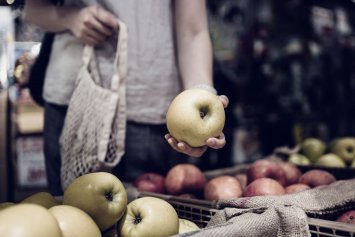 Kvindehånd der holder et æble i supermarkedet