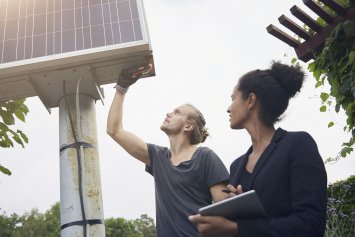 En håndværker og en kvindelig husejer, der kigger på et solcelleanlæg